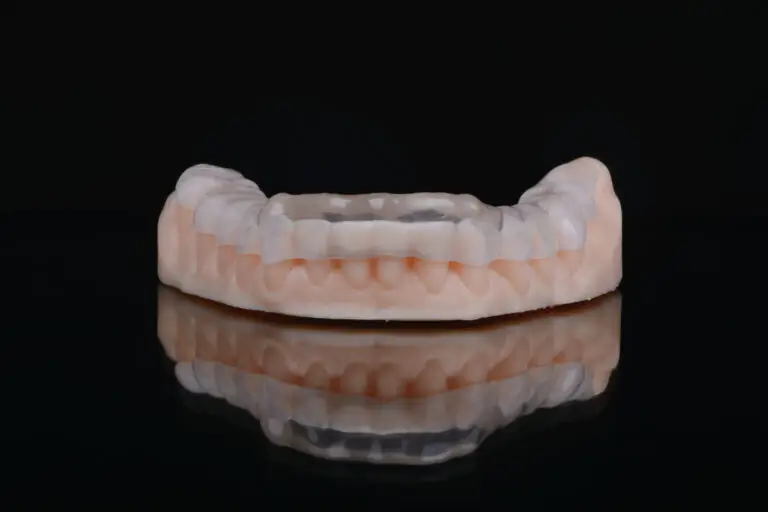 Printed transparent dental cap made of polymer on a light colorful background. Dental splint against bruxism